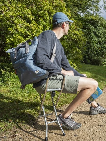 Man sat on a National Trust stool wiath a Roka bag and grand adventure map