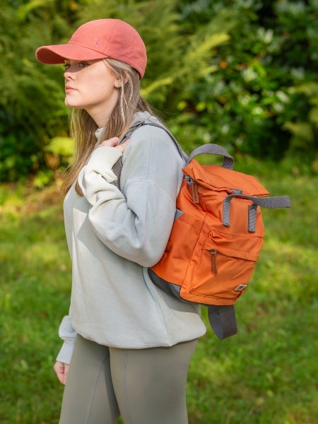 A woman wearing an orange National Trust baseball cap and an orange ROKA backpack