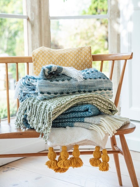 National Trust yellow and blue throws on a wooden bench