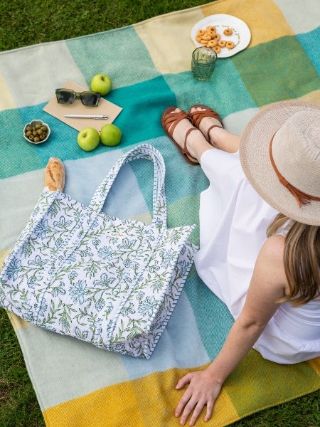 Woman on a National Trust waterproof green check picnic blanket. 