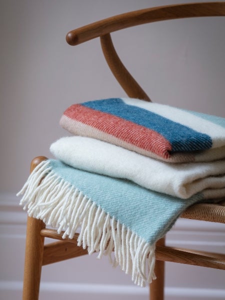 A blue and earth tone National Trust throw displayed on a chair.