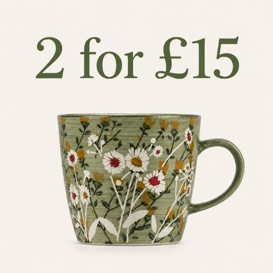 A green mug with a white daisy floral pattern, on a wood coaster.