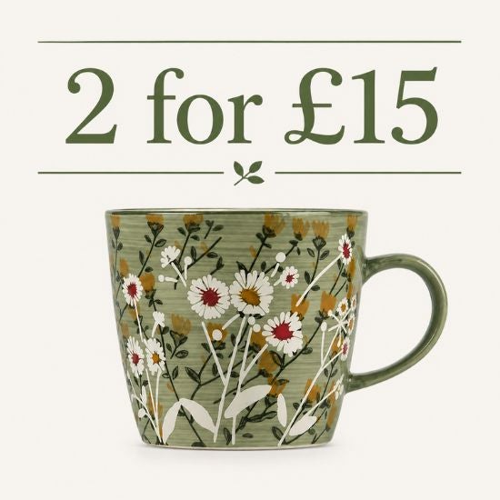 A green mug with a white daisy floral pattern, on a wood coaster.