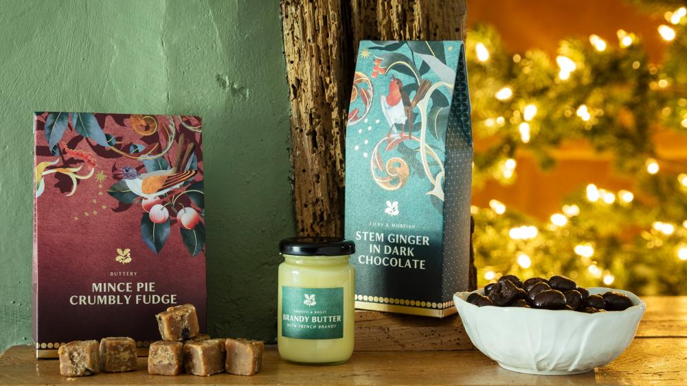 National Trust food & drink - image shows three festive treats from our Christmas food range arranged on a kitchen work surface, including the Christmas Pickle, Marmalade & Boxing Day Chutney.  