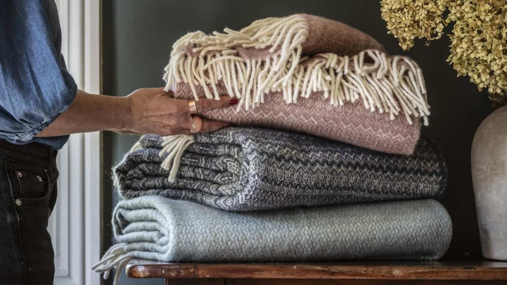 National trust throws in mustard, burnt organe and grey on a wooden sideboard