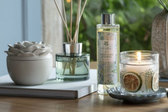 Home fragrance - image shows the Coffee and Bergamot Reed Diffuser on a windowsill, with a soft light shining through the window and illuminating the retro, vintage inspired glass bottle.