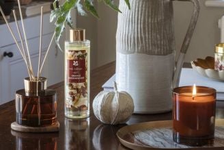 Home fragrance - image shows the Coffee and Bergamot Reed Diffuser on a windowsill, with a soft light shining through the window and illuminating the retro, vintage inspired glass bottle.