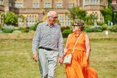 Gifts for grandparents - image shows older couple sat on a bench at a National Trust property, reading a guidebook.
