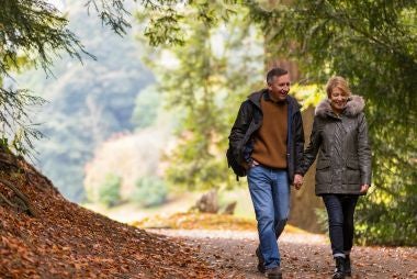 Gifts for grandparents - image shows older couple sat on a bench at a National Trust property, reading a guidebook.