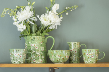A collection of Gisela Graham wild daisy mugs and ceramics on a wooden shelf