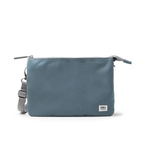 Blue-grey recycled canvas crossbody pouch with an adjustable webbing strap, zip-top closure, and compact rectangular design featuring a minimalist front panel and woven logo label.