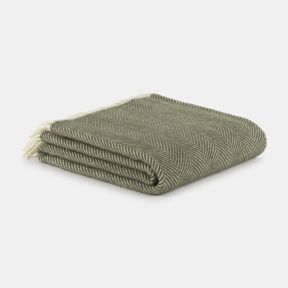 Folded sage green throw blanket with a classic herringbone weave, neatly stacked on a light grey background. Soft and cosy in appearance, the blanket features subtle cream fringe tassels and a timeless textured design, ideal for adding warmth and style to