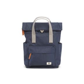 Roka London backpack in navy blue with light grey carry handles, a roll-top opening, front zip pocket, side pockets and tan zip pulls. Lightweight, practical design featuring the Roka London logo on the front pocket.