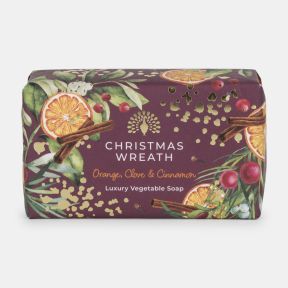 Christmas Wreath luxury vegetable soap in festive burgundy packaging decorated with dried orange slices, cinnamon sticks, red berries, greenery, and gold accents. Scented with orange, clove and cinnamon.