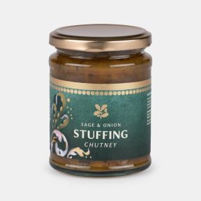 Jar of sage and onion stuffing chutney, featuring a clear glass jar with a gold lid and a dark green label decorated with festive botanical artwork, showing chunky chutney inside and isolated on a white background.