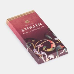 Festive milk chocolate bar in red seasonal packaging with decorative gold accents and Christmas-themed illustrations, shown at an angled view.