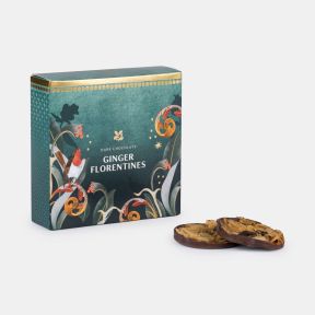 Dark chocolate ginger Florentines in a festive teal gift box featuring a robin, seasonal botanical illustrations and gold accents, displayed alongside two chocolate-coated Florentines.