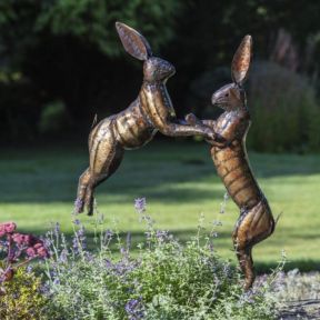 Metal boxing hare ornament and sculpture in a summer garden setting