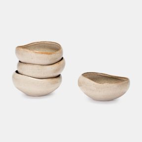 Set of four oatmeal-coloured ceramic bowls with a speckled glaze finish and organic curved shape. Three bowls are stacked while one is displayed separately, highlighting the artisanal design and neutral tones against a plain light grey background.