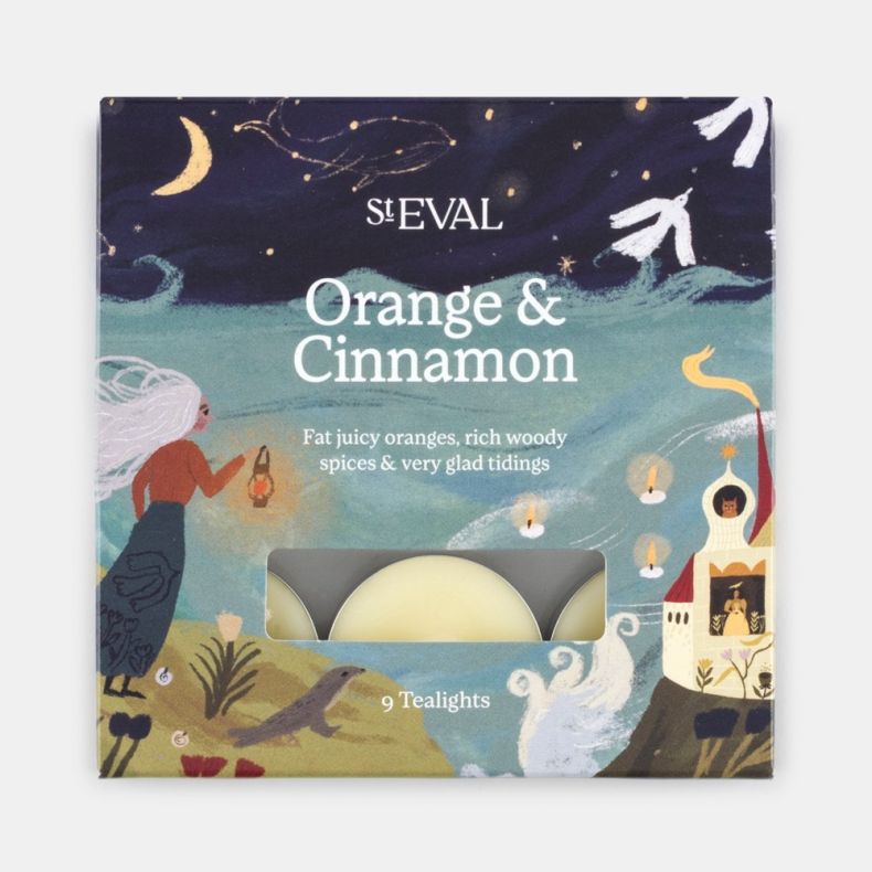 Front view of a St Eval Orange & Cinnamon scented tealight pack displayed against a light background. The decorative box features an illustrated festive landscape with a moonlit sky, ocean waves, candles and seasonal motifs in navy, teal, cream and gold t