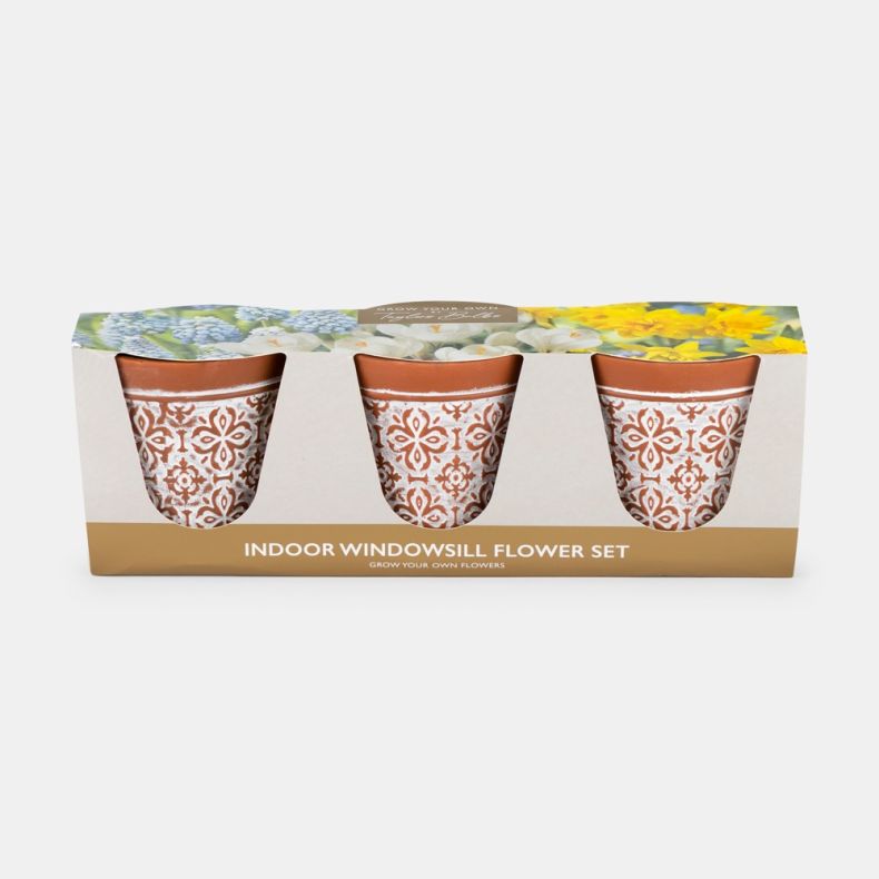 Indoor windowsill flower growing gift set displayed against a light background, featuring three terracotta plant pots decorated with a white ornamental tile-inspired pattern. The pots are presented in a cardboard sleeve with cut-out windows that reveal ea