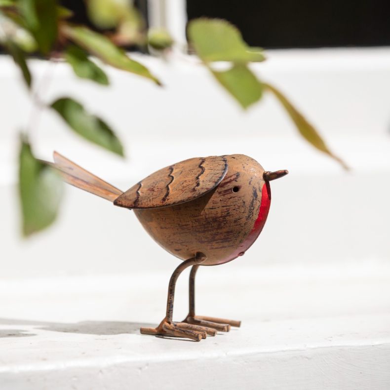 Metal robin ornament with an antique copper-effect finish, featuring a round body, red breast detail, engraved feather markings, wire legs and tail, and a freestanding design displayed on a windowsill.