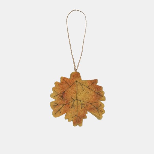 Autumn leaf hanging decoration displayed against a light background, featuring a maple-style leaf shape in warm shades of golden yellow and soft burnt orange with printed vein detailing throughout. The decoration has a textured felt-like finish and is sus