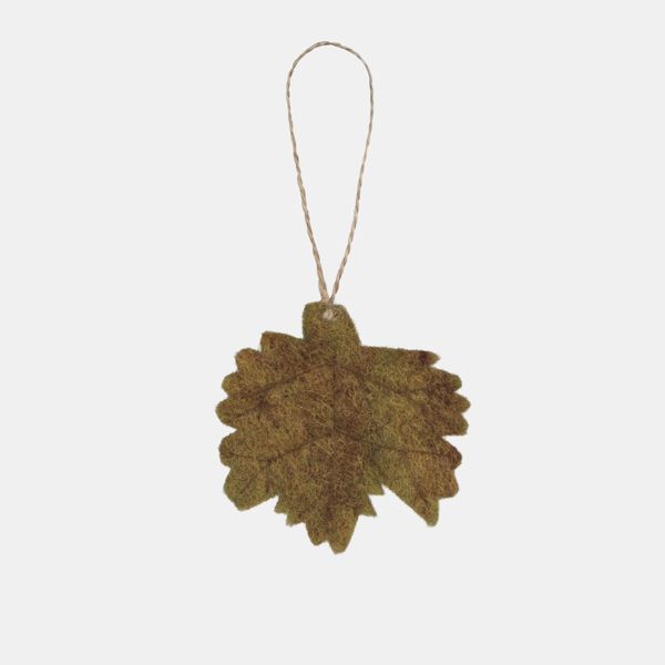 Autumn leaf hanging decoration displayed against a light background, featuring a maple-style leaf shape in muted olive green and warm brown tones with a textured felt-like finish. The decoration is suspended from a natural twine loop and showcases subtle 