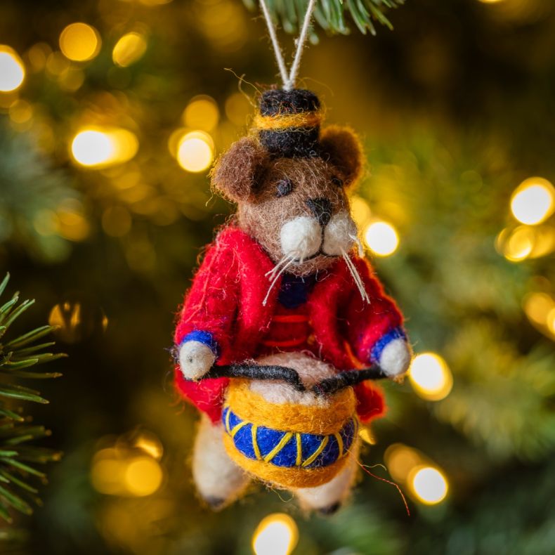 Felt mouse drummer Christmas hanging decoration displayed on a Christmas tree, featuring a brown wool-effect body, black top hat with gold trim, red military-style jacket, blue and gold drum with drumsticks, white whisker detailing, and handcrafted needle
