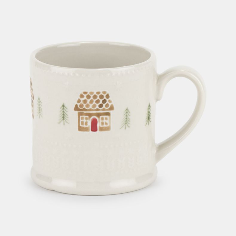 Cream ceramic mug with an embossed textured finish, featuring a festive gingerbread house and pine tree pattern in soft brown, green and red tones, with a curved handle and classic cylindrical shape.
