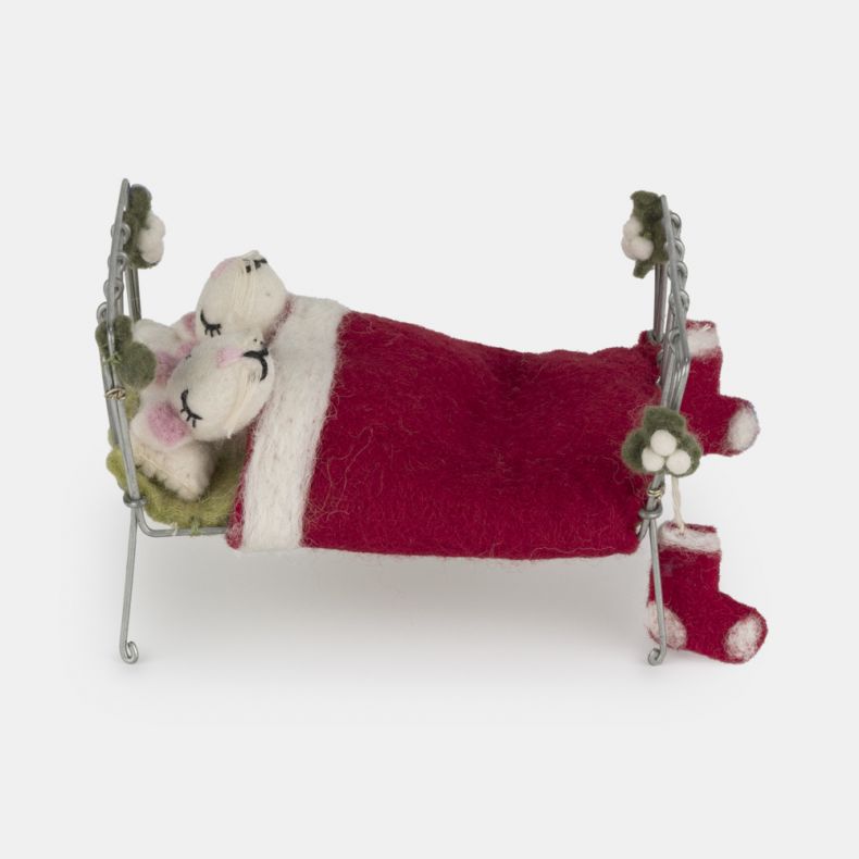 Felt mice Christmas hanging decoration in a miniature metal bed, featuring two white wool-effect mice tucked beneath a red felt blanket, with embroidered closed-eye detailing, soft pink ears, festive stocking accents, and holly-inspired decoration on the 