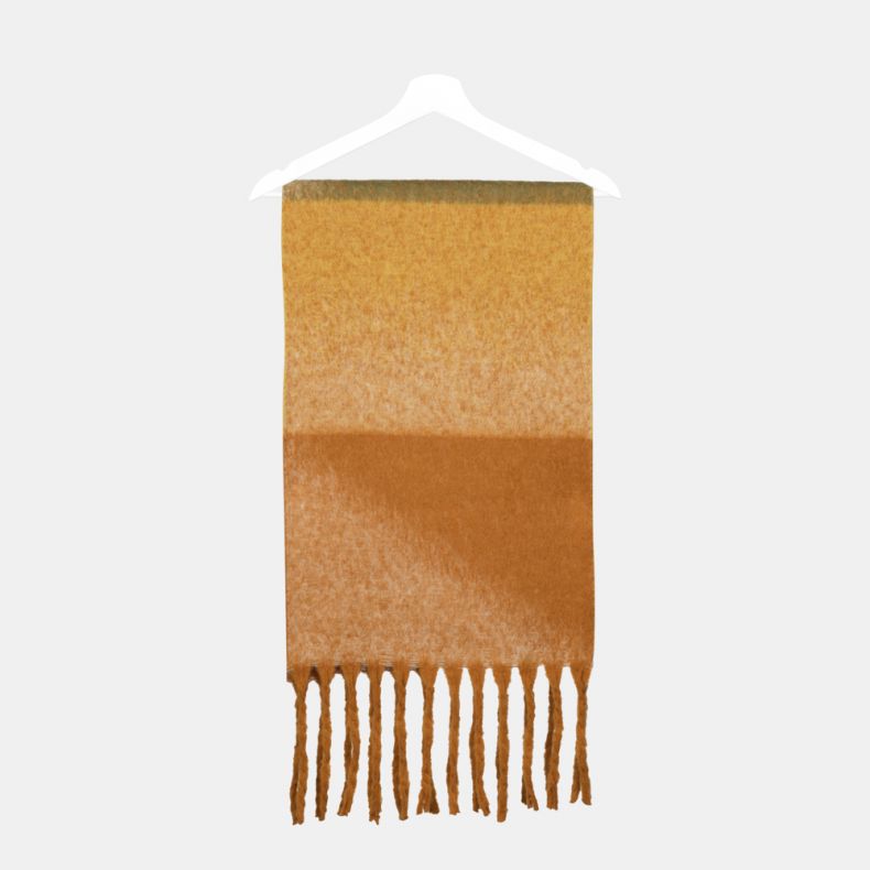 Orange and mustard ombre scarf folded on a hanger, featuring blended shades of mustard yellow, burnt orange and soft cream, a brushed texture, and long fringed ends.
