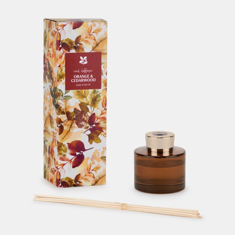 Orange & Cedarwood reed diffuser gift set displayed on a light background, featuring a tall rectangular box with an autumn leaf pattern and a burgundy label reading “reed diffuser ORANGE & CEDARWOOD made in the UK,” alongside an amber glass diffuser bottl