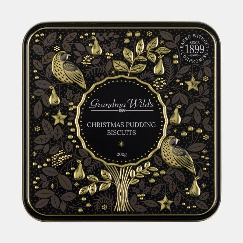 Grandma Wild's Christmas Pudding Biscuits gift tin lid featuring embossed gold birds, pears, stars and festive foliage on a black background, with ornate seasonal detailing and decorative keepsake tin design.