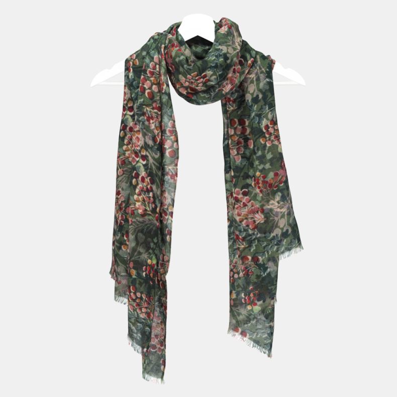 Green botanical print scarf with an all-over foliage and berry pattern, featuring soft lightweight fabric, fringed edges, and a long rectangular design draped on a hanger.