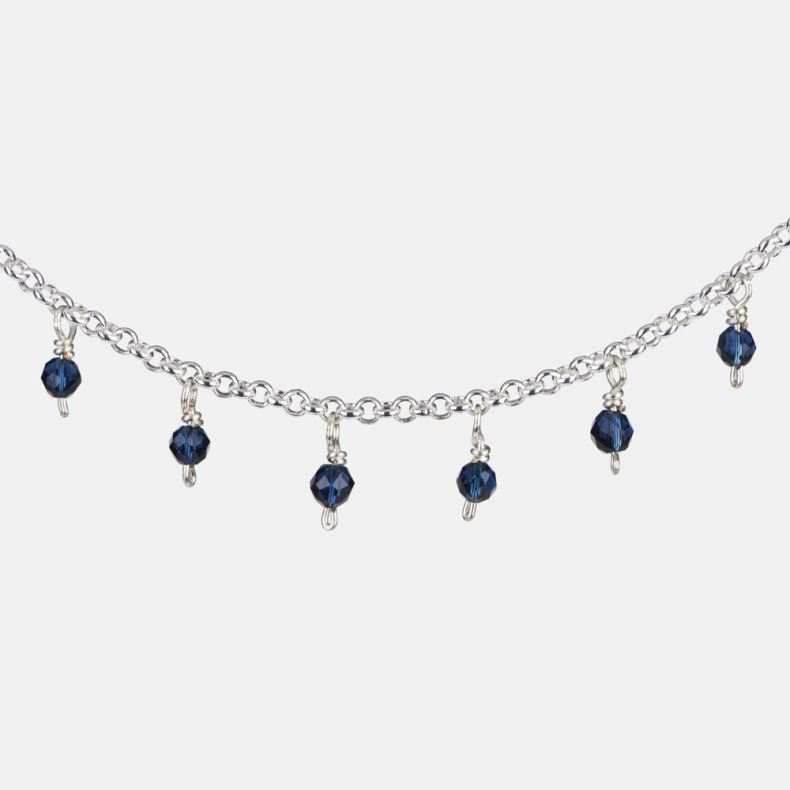 Silver-tone charm bracelet shown in a close-up view, highlighting faceted navy blue crystal bead drops suspended from a delicate chain with a polished silver-tone finish.