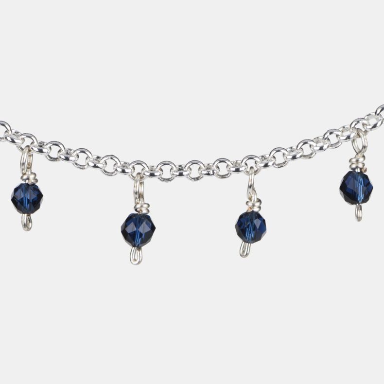 Silver-tone charm bracelet shown in a detailed close-up view, highlighting faceted navy blue crystal bead charms suspended from a polished silver-tone chain with delicate link detailing.