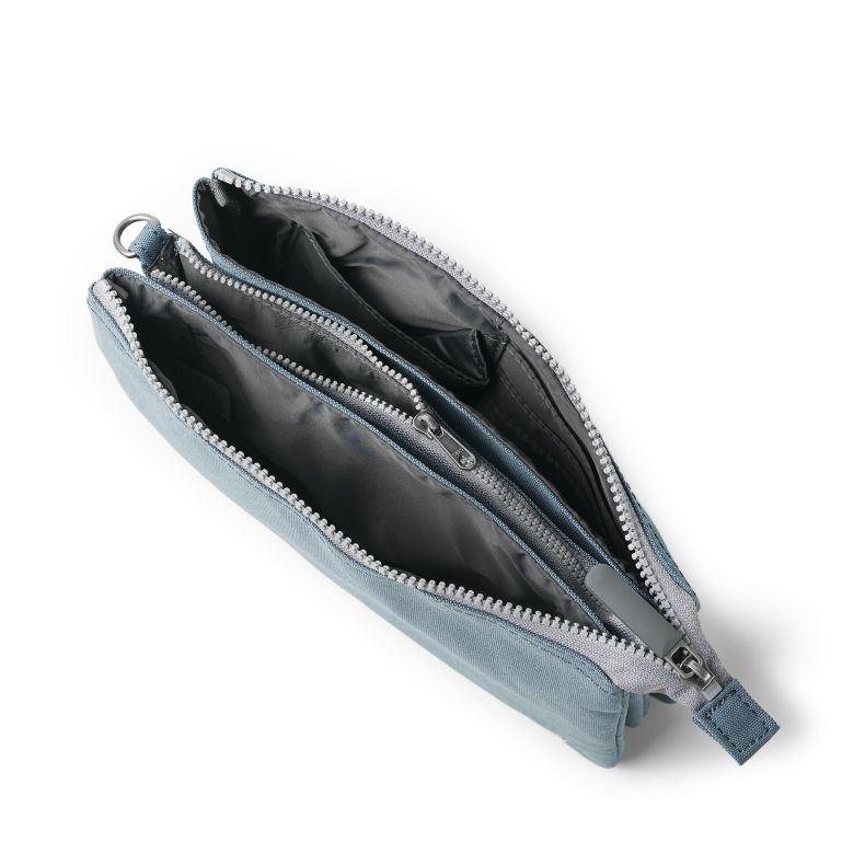 Blue-grey recycled canvas crossbody pouch shown from an overhead view, highlighting the double zip-top compartments, internal zip pocket, slip pockets, card slots, and organised multi-compartment interior.