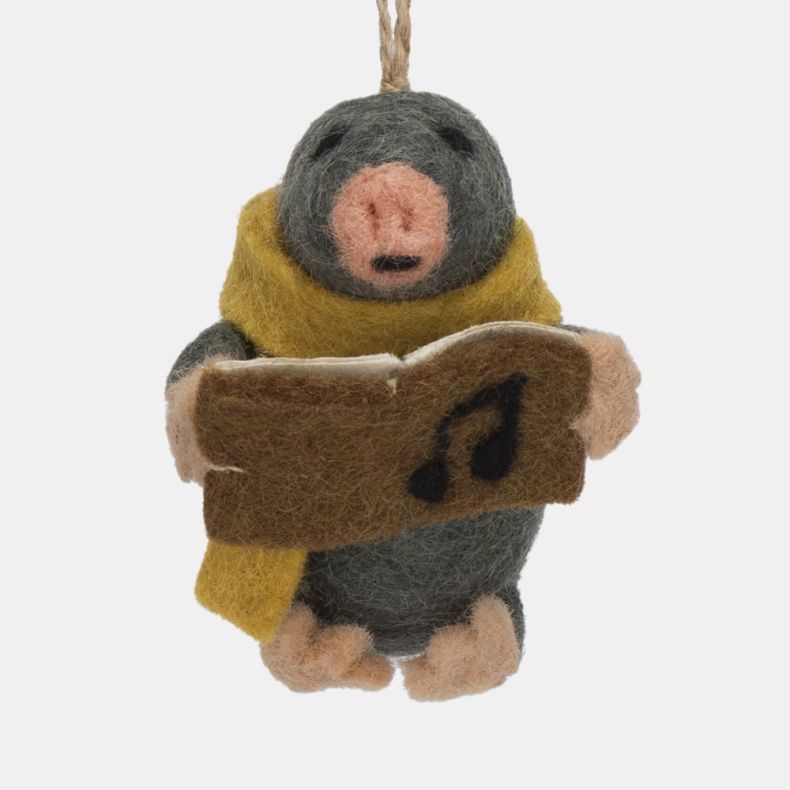 Felt mole Christmas hanging decoration shown in a close-up front view, featuring a dark grey wool-effect body, mustard yellow scarf, pink nose and paws, and a brown carol songbook with black musical note detail, finished with handcrafted needle-felted det