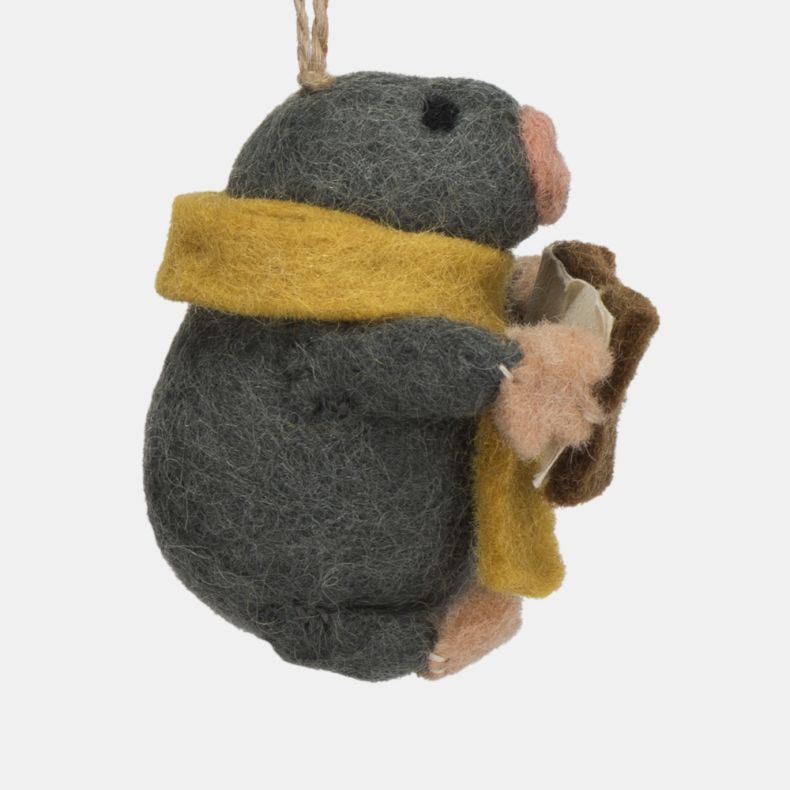 Felt mole Christmas hanging decoration shown in a close-up side view, featuring a dark grey wool-effect body, mustard yellow scarf, pink nose and paws, and a brown carol songbook, finished with handcrafted needle-felted detailing and a rustic twine hangin