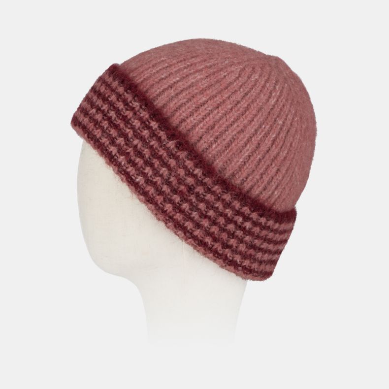 Pink ribbed knit beanie hat with a chunky textured turn-up brim in contrasting burgundy and pink tones, featuring a soft fluffy yarn and cosy winter design shown from an angled side view.