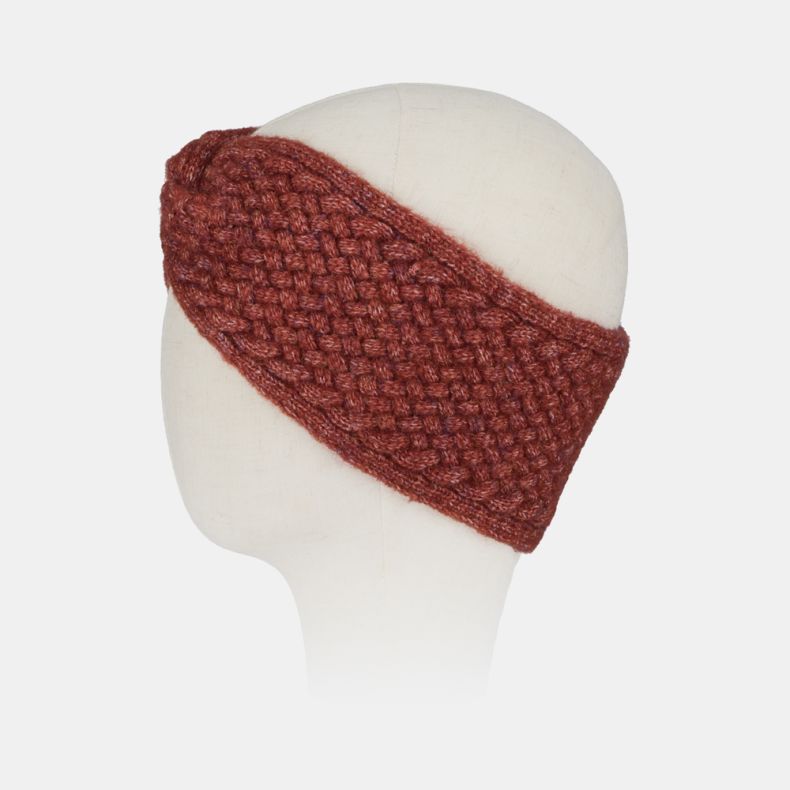 Rust orange knitted headband with a textured basket-weave stitch pattern and soft marl finish, shown from an angled side view with a twisted knot detail for cosy cold-weather styling.