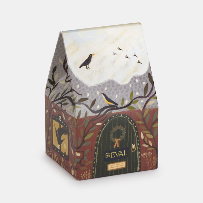 St Eval festive candle gift box featuring illustrated woodland birds, winter foliage, and a snow-covered cottage scene, presented in decorative seasonal packaging with rich green, burgundy and cream tones.