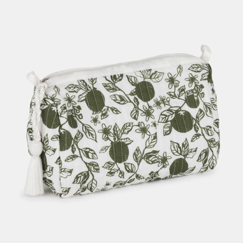 White quilted toiletry bag with a green orangery print featuring citrus fruit, leaves, and blossoms. Zip-top design with a decorative white tassel pull and softly structured shape, shown at an angled view against a light grey background.