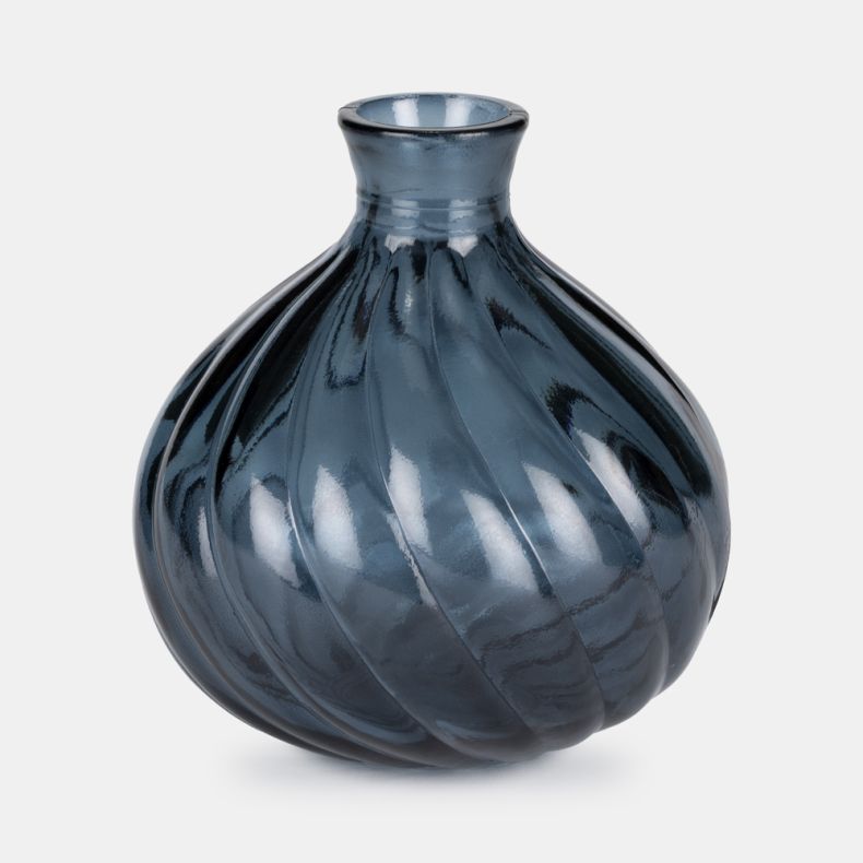 Glossy dark blue glass vase with a rounded bulb shape and narrow neck. Twisted ribbed detailing wraps around the body, creating a spiral effect. Decorative vase photographed on a light grey background with reflective finish and smooth texture.