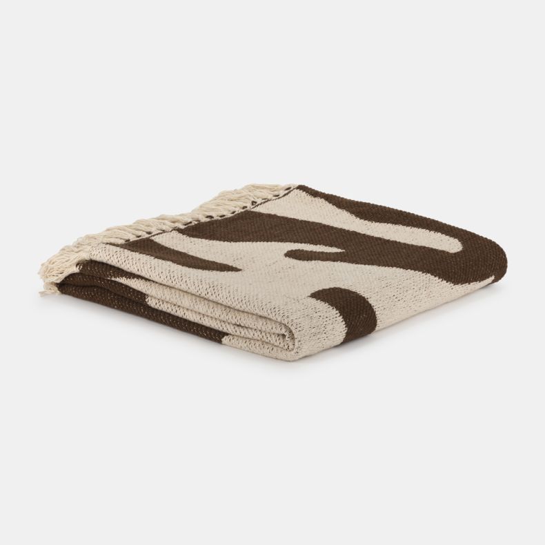 Folded Recycled Alma Abstract Throw in chocolate brown and natural cream, featuring a bold abstract pattern and soft woven texture. Neatly folded with cream fringe tassels visible, this cosy throw adds warmth, texture and contemporary style to sofas, beds