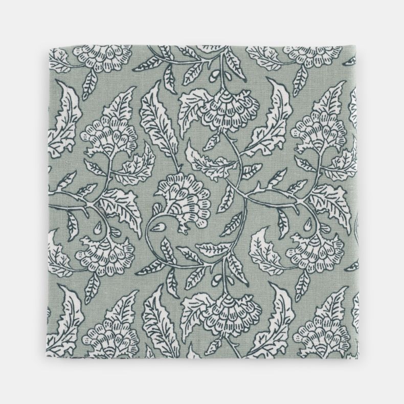 Close-up of a Kilburn & Scott napkin featuring an elegant heritage-inspired floral and bird pattern in soft sage green and white. The woven fabric showcases intricate botanical detailing and a timeless country-style design, making it ideal for coordinatin