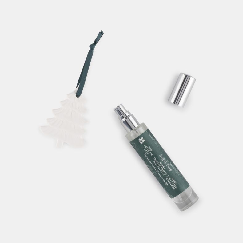 Frosted Pines fragrance decoration set shown with a white ceramic Christmas tree ornament and 15ml scented spray bottle, featuring embossed tree detailing, teal hanging ribbon, and festive home fragrance design.