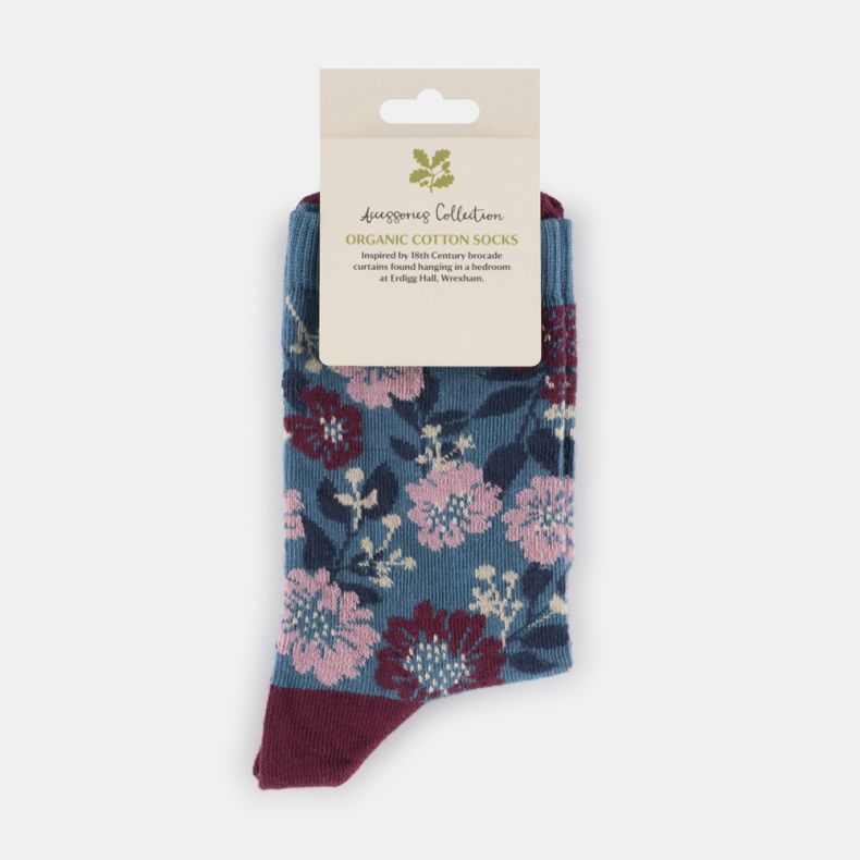 Blue floral organic cotton socks with pink and burgundy flower pattern, featuring a teal blue background, contrasting burgundy heel and toe, displayed folded with retail packaging.