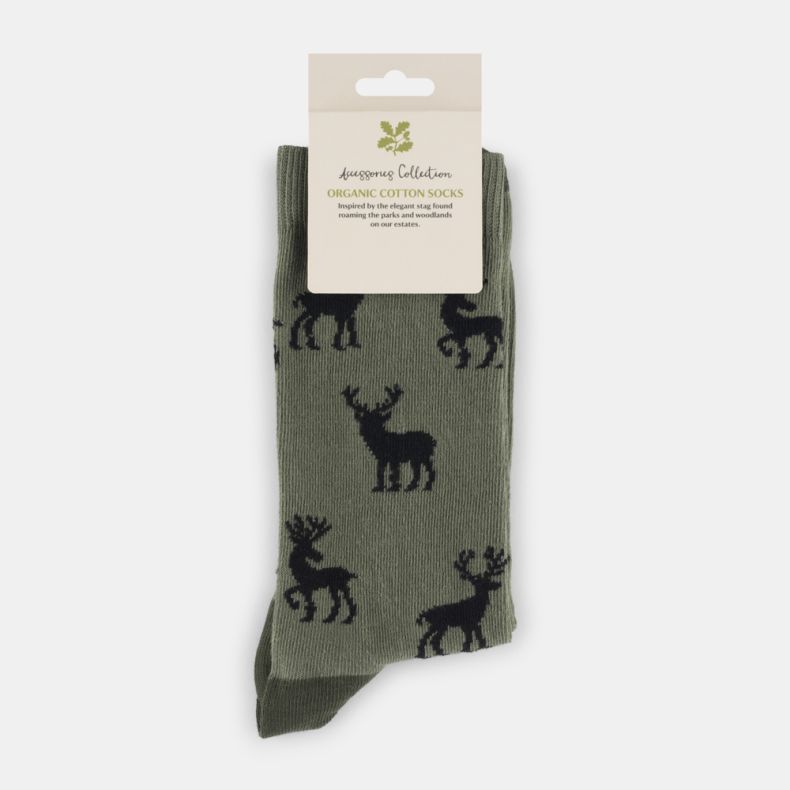 Olive green organic cotton socks with a repeating black stag motif, featuring a ribbed cuff and matching dark green heel and toe accents, displayed folded with retail packaging.